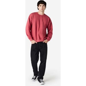 A man wearing a red Gildan Heavy Blend adult crewneck sweatshirt and black jeans, with a logo on the sweatshirt.