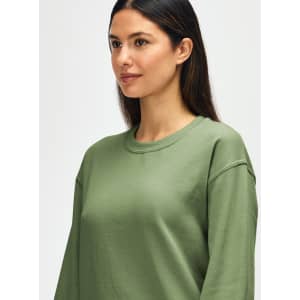 An olive green Gildan Heavy Blend adult crewneck sweatshirt with a model showcasing its fit and design.