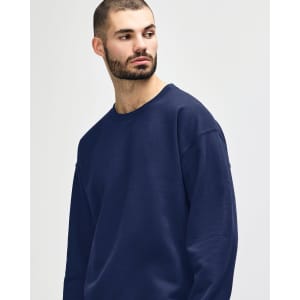 A woman wearing a navy Gildan Heavy Blend Adult Crewneck Sweatshirt, featuring a logo on the front.