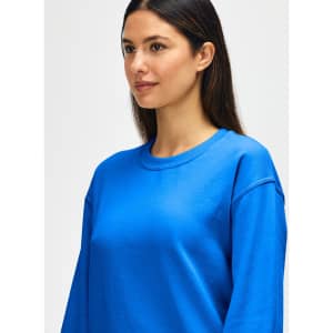 A blue Gildan Heavy Blend adult crewneck sweatshirt on a model with a neutral background, featuring a logo.