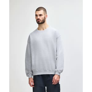A grey Gildan Heavy Blend Adult Crewneck Sweatshirt displayed on a model, featuring a classic crew neckline and long sleeves.
