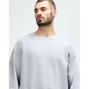 A grey Gildan Heavy Blend adult crewneck sweatshirt displayed on a model posing thoughtfully. It features a logo.
