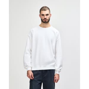 A white crewneck sweatshirt with long sleeves, featuring a relaxed fit and a simple design. It has a logo.