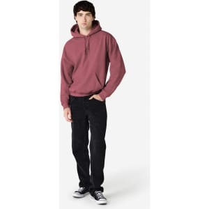 A maroon hooded sweatshirt is worn by a model paired with black jeans and sneakers, featuring a logo.