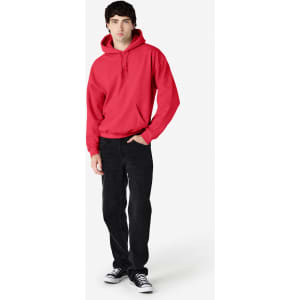 A red hooded sweatshirt worn by a model, paired with black trousers and shoes, featuring a logo on the garment.