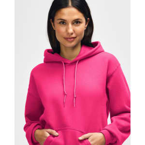 A bright pink hooded sweatshirt featuring a front pocket and drawstrings, worn by a model adjusting the hood.