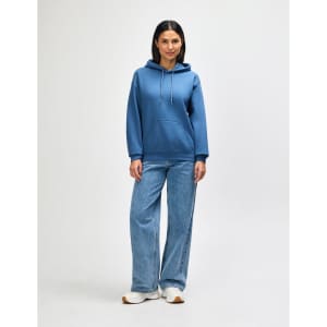 A blue hooded sweatshirt with a kangaroo pocket, paired with light blue jeans and white shoes.