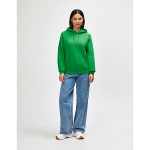A green hooded sweatshirt with a front pocket and drawstring, worn with blue jeans and white sneakers.