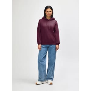 A maroon hooded sweatshirt with a kangaroo pocket, worn by a model paired with black jeans and sneakers.
