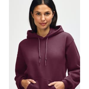 A hooded sweatshirt in a deep burgundy colour, featuring a drawstring hood and an individual adjusting the neckline.