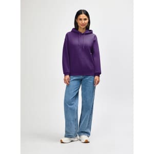 A purple hooded sweatshirt with a front pocket, worn by a model. The model is paired with black jeans and sneakers.