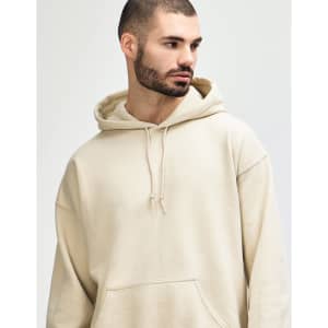 A beige hooded sweatshirt is modelled by a young woman with long hair, staring directly at the camera.