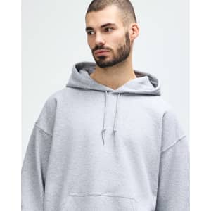 A grey Gildan Heavy Blend adult hooded sweatshirt on a male model, featuring a drawstring hood and a logo.