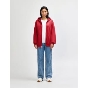 A red Gildan Heavy Blend adult full zip hooded sweatshirt on a model. The model wears black pants and sneakers.