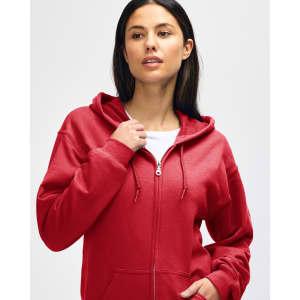 A red Gildan Heavy Blend adult full zip hooded sweatshirt on a model adjusting the hood. The sweatshirt features a logo.