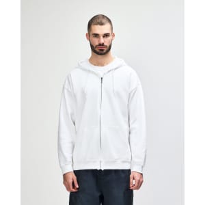 A white full zip hooded sweatshirt on a model, featuring a front pocket and a drawstring hood.