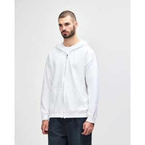 A white Gildan Heavy Blend adult full zip hooded sweatshirt is displayed on a model. The sweatshirt features a hood and a relaxed fit.