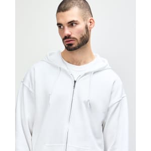 A white Gildan Heavy Blend adult full zip hooded sweatshirt worn by a model adjusting the hood.