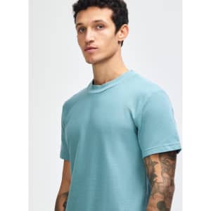 A teal unisex pique mockneck t-shirt with short sleeves, featuring a logo on the front.