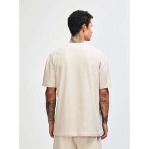 A unisex mockneck t-shirt in a soft beige colour, featuring short sleeves and a plain back. It has a logo.