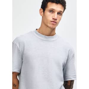 A unisex grey pique mockneck T-shirt with short sleeves, featuring a logo on the front.