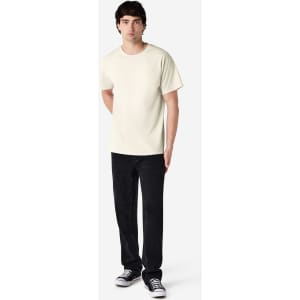 An adult t-shirt in cream colour displayed on a model wearing black pants and shoes. The shirt features a logo.