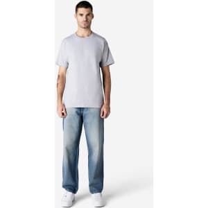 A man stands wearing a light grey Gildan Ultra Cotton Adult T-Shirt and blue jeans, with white sneakers.