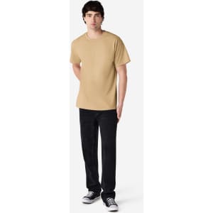 A male model wearing a plain beige Gildan Ultra Cotton adult t-shirt paired with black pants and Converse shoes.