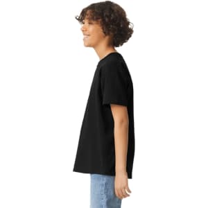 A black youth short sleeve T-shirt displayed on a person from the side, featuring a plain design and a logo.