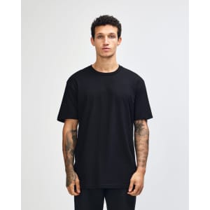 A model wearing a black unisex short sleeve t-shirt, paired with blue jeans. The t-shirt features a logo.