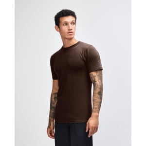 A brown unisex fine jersey short sleeve T-shirt displayed on a model from the side. Features a logo.