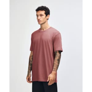 A side view of a woman wearing a rose pink unisex short sleeve T-shirt. The shirt has a simple design and a logo.