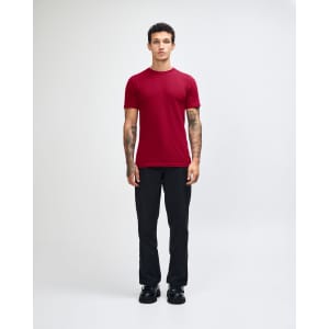 A red unisex short sleeve t-shirt worn by a model, paired with beige cargo pants and black shoes.