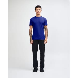 A unisex fine jersey short sleeve T-shirt in navy blue, worn by a model with curly hair, paired with beige pants.