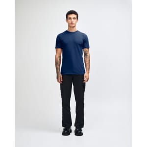 A model wearing a navy unisex fine jersey short sleeve t-shirt and tan wide-leg pants. The t-shirt has a logo.