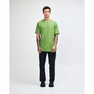 A unisex fine jersey short sleeve T-shirt in vibrant green, worn by a model in casual denim. It features a logo.