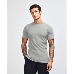A grey unisex short sleeve T-shirt displayed on a model with hands in pockets, featuring a simple design.