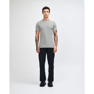 A grey unisex short sleeve t-shirt displayed on a model wearing loose-fitting denim jeans and sneakers.