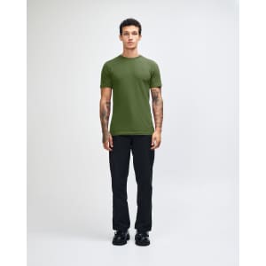A green unisex short sleeve t-shirt worn by a model, paired with blue jeans and black shoes. Branding visible.