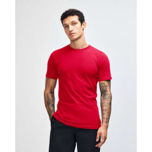 A red unisex fine jersey short sleeve t-shirt displayed on a model with curly hair. It features a logo.