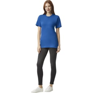 A woman stands wearing a blue unisex fine jersey short sleeve t-shirt and black leggings, with white shoes.