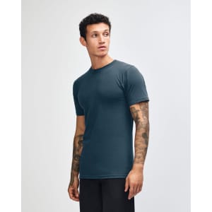 A unisex fine jersey short sleeve T-shirt in navy blue, featuring a logo on the side. Model standing sideways.