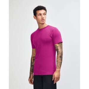 A unisex fine jersey short sleeve t-shirt in vibrant purple, worn by a model posing sideways. The shirt features a logo.