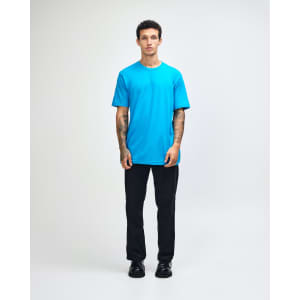 A man wears a bright turquoise unisex fine jersey short sleeve T-shirt, with a logo on the shirt.