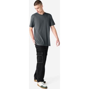 A unisex short sleeve T-shirt in grey paired with black cargo pants, featuring a simple design and a logo.