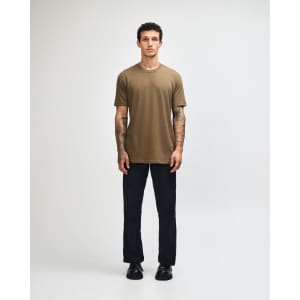 A model wearing a unisex short sleeve T-shirt in olive green, paired with black cargo pants and sneakers.