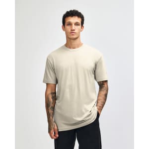 A unisex short sleeve T-shirt in a neutral beige colour, displayed on a model. It features a simple design and logo.