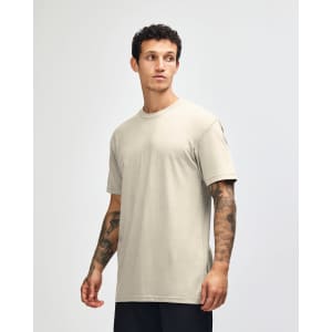 A unisex beige CVC short sleeve T-shirt displayed on a model, featuring a logo.
