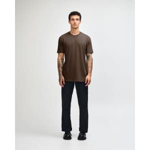 A unisex short sleeve T-shirt in brown, displayed by a model, paired with dark cargo pants and footwear.