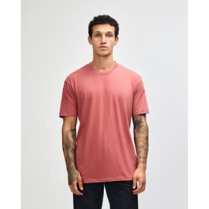 A unisex CVC short sleeve t-shirt in a muted reddish tone, featuring a simple design and a logo.